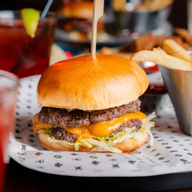 Drive in burger.Two Smashed Beef Patties / Hand-formed ‘AAA’ Alberta Beef Grain-Fed / Ground Ribeye and Chuck / Melted Cheddar Cheese / Iceberg Lettuce / Tomato / Drive-in Burger Sauce / Fresh-made Relish / Served on a Brioche Bun / With a Side of Fries