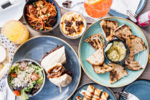 Hudson's Summer Discovery Menu 2026 — honey pistachio whipped ricotta, garlic parmesan fries, ancho chipotle taquitos, bourbon peach pork belly bites, stacked rib panini, and butter tart tiramisu